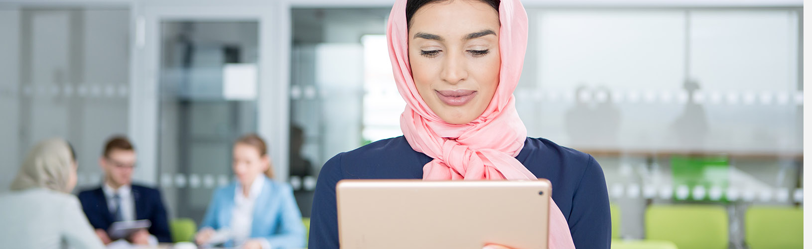 Muslim woman reviews internal audit management best practices on a tablet.